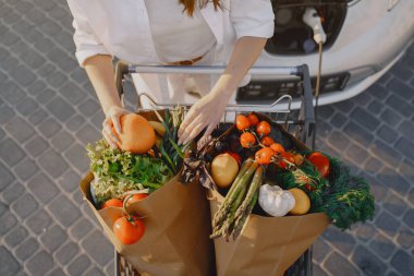 Elektrikli benzin istasyonunda kadın elektro arabayı şarj ediyor.