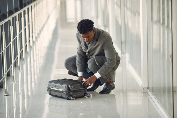 Elegant black man at the airport with a suitcase — Stock Photo, Image