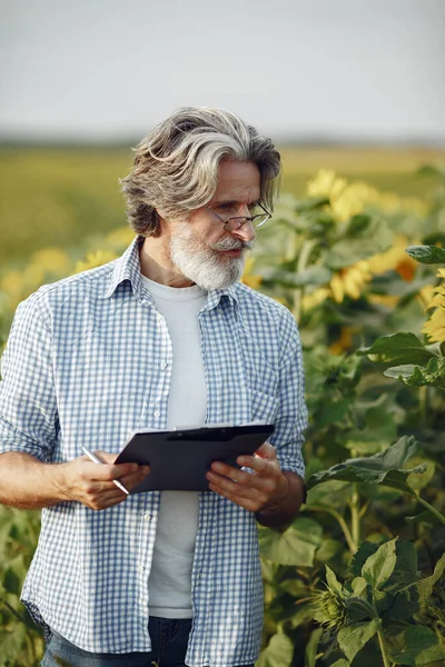 Antiguo granjero en camisa de pie en el campo con cuaderno —  Fotos de Stock