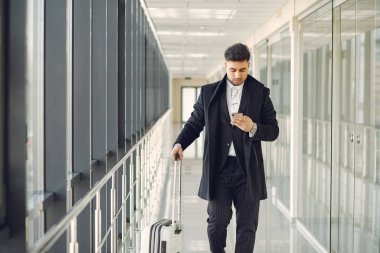 Havaalanında bavullu şık bir adam.