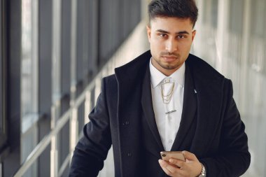 Ofiste çalışan şık bir işadamı ve telefonu kullanıyor.