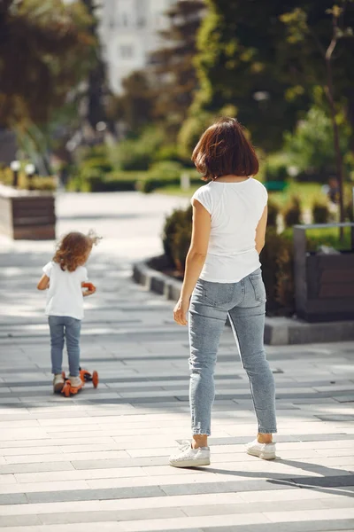 Madre con hija en un parque de primavera con patín — Foto de Stock