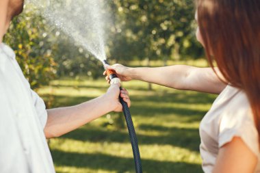 Bahçede çimleri sulayan insanlar.