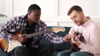 İki arkadaş akustik gitar çalmayı öğreniyor.