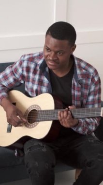 Evde gitar çalan genç bir Afrikalı.