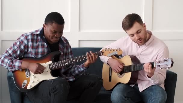 Два друга учатся играть на акустической гитаре — стоковое видео