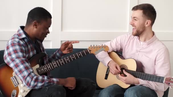 Hombre afroamericano enseñando a su pequeño hijo a tocar la guitarra en  casa — Vídeo de stock © prostooleh #478823538