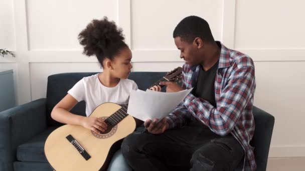 Un Afro-Américain apprend à sa petite fille à jouer de la guitare à la maison — Video