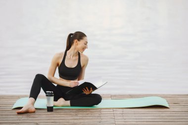 Su kenarında yoga yapan bir kadın.