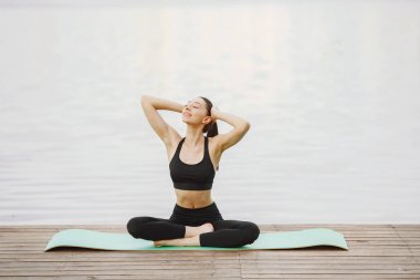 Su kenarında yoga yapan bir kadın.