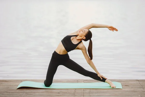 Femme pratiquant le yoga avancé près de l'eau — Photo