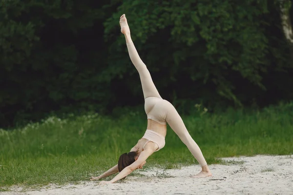 Donna che pratica yoga avanzato in una spiaggia — Foto Stock