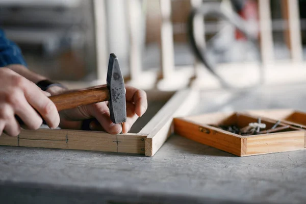 Carpintero martillando un clavo en un taller — Foto de Stock