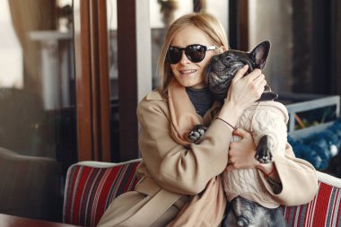 Kahverengi ceketli, siyah bulldog giyen zarif bir kadın.