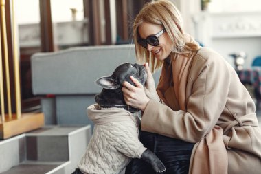 Kahverengi ceketli, siyah bulldog giyen zarif bir kadın.