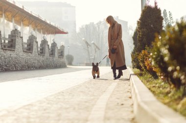 Kahverengi ceketli, siyah bulldog giyen zarif bir kadın.