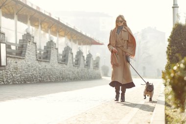 Kahverengi ceketli, siyah bulldog giyen zarif bir kadın.