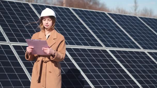 Young woman with checklist standing at solar plant — Wideo stockowe