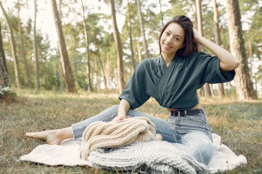 Yaz parkında oturan ve örgü ören bir kız.