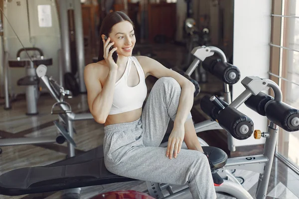 Uma linda garota sentada com telefone em um ginásio — Fotografia de Stock