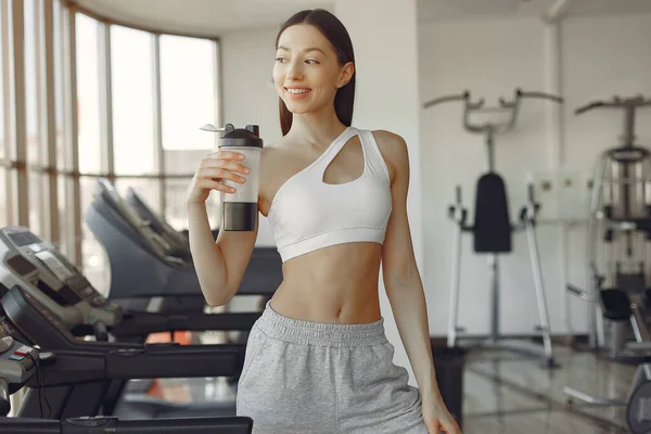 A beautiful girl standing in a gym with bottle of water — Stock Photo, Image