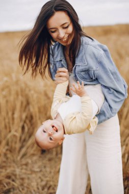 Anne ve kızı sonbahar tarlasında oynuyorlar.