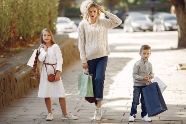 Şehirde alışveriş torbası taşıyan çocuklu bir anne.