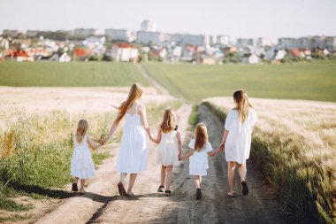 Sonbahar tarlasında kızlarıyla oynayan anneler.