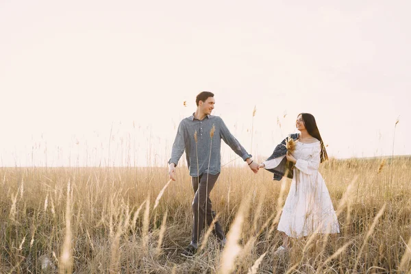 Gelukkig paar in liefde in tarweveld bij zonsondergang — Stockfoto