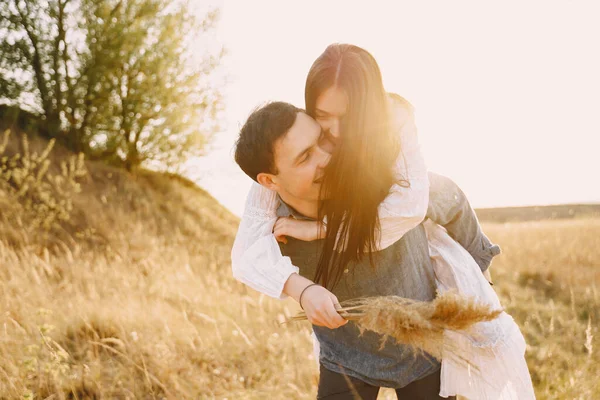 Gelukkig paar in liefde in tarweveld bij zonsondergang — Stockfoto