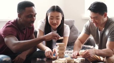 Genç çok ırklı insanlar içeride Jenga oyunu oynuyorlar