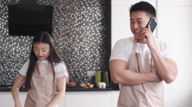 Evdeki mutfakta birlikte yemek pişiren mutlu Asyalı genç çiftin portresi.