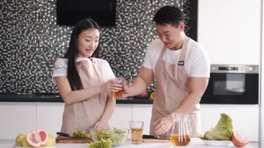 Evdeki mutfakta birlikte yemek pişiren mutlu Asyalı genç çiftin portresi.