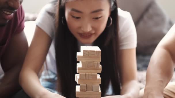 Unga multietniska människor spelar jenga spel inomhus — Stockvideo