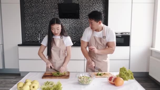 Portret van gelukkig jong aziatisch paar koken samen in de keuken thuis — Stockvideo