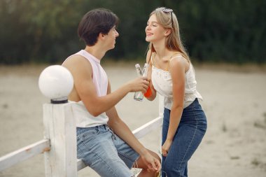 Çiftler sahilde içki içerken eğlenirler.