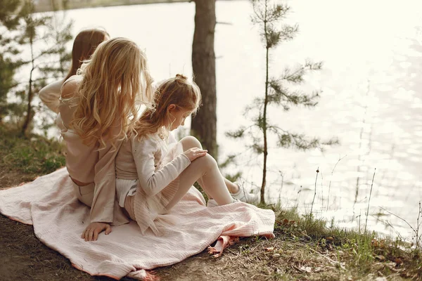 Elegant mother with children sitting by the water — Stock Photo, Image