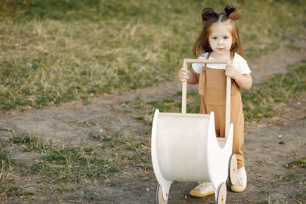 Bonita menina brincando em um parque com carruagem branca — Fotografia de Stock