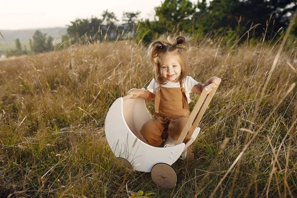 Bonita menina brincando em um parque com carruagem branca — Fotografia de Stock