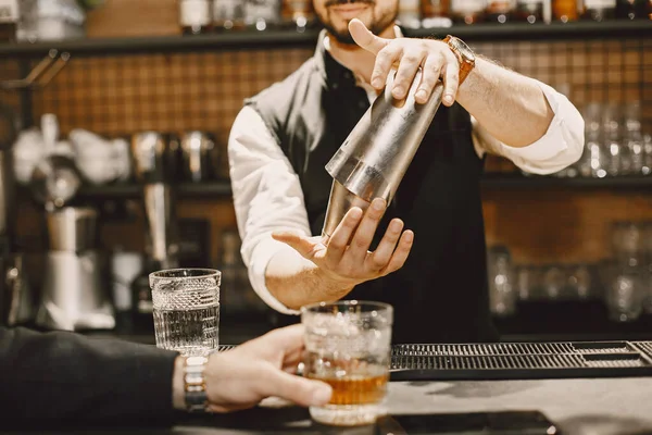 Barman nalewa brązowy napój alkoholowy do szklanki — Zdjęcie stockowe