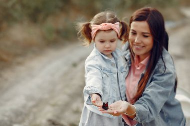 Anne ve küçük kızı sonbahar tarlasında oynuyorlar.