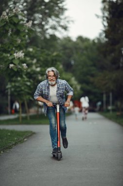 Bir yaz parkında scooterlı yaşlı bir adamın portresi.