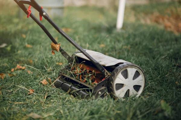 나이든 사람은 잔디깎는 기계로 마당의 잔디를 깎는다 — 스톡 사진