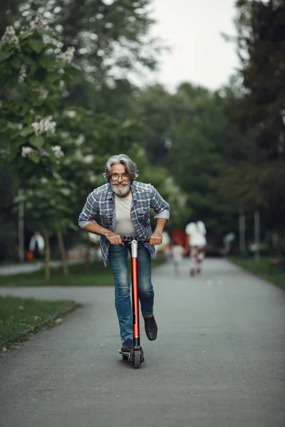 Retrato de homem idoso com chute scooter em um parque de verão — Fotografia de Stock