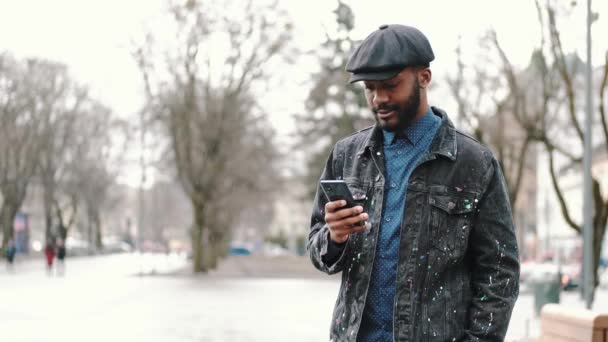 Stijlvolle Afrikaanse jongeman buiten met zijn smartphone — Stockvideo