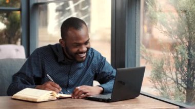 Kafede bilgisayarla uzaktan çalışan bir iş adamı.