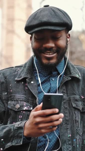 Hombre afroamericano con sombrero escuchando música al aire libre — Vídeos de Stock