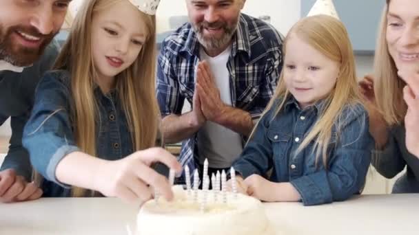 Föräldrar tittar på flickor sätta ljus på födelsedagstårta — Stockvideo