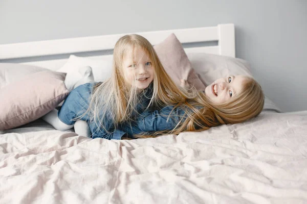 Two cute little sisters playing on bed with pillows — Stock Photo, Image