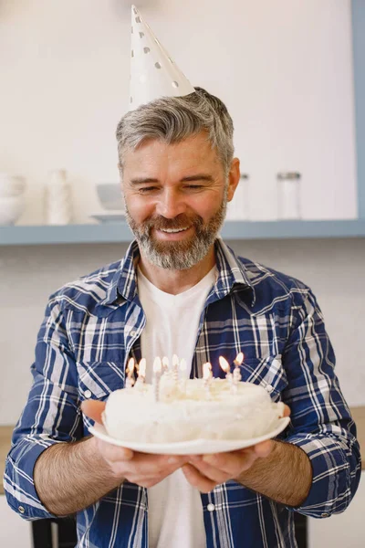 Man in a party-hat keep a cake with a candles — Stock Photo, Image